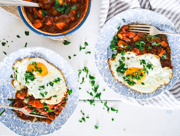 homemade baked beans on plates, topped with a fried egg and parsley. Gluten-free, refined sugar free and gut loving.
